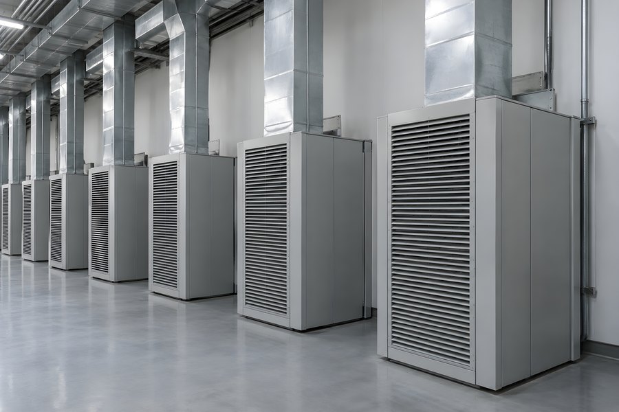 Row of computer room air handler cooling units with overhead insulated ductwork in a data center mechanical room