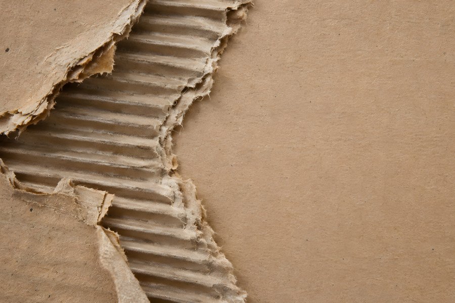 Torn corrugated cardboard texture with exposed flutes and blank brown surface for copy space