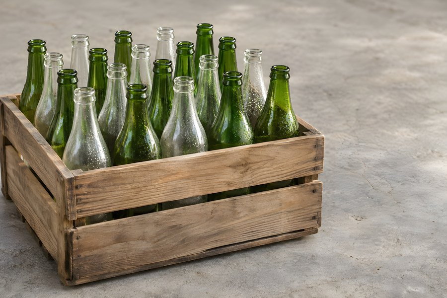 Wooden crate filled with empty green and clear glass bottles for reusable and returnable packaging