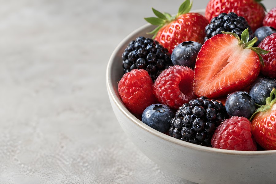 Bowl of Fresh Mixed Berries with Strawberries, Blackberries, Blueberries and Raspberries on Textured Background with Copy Space