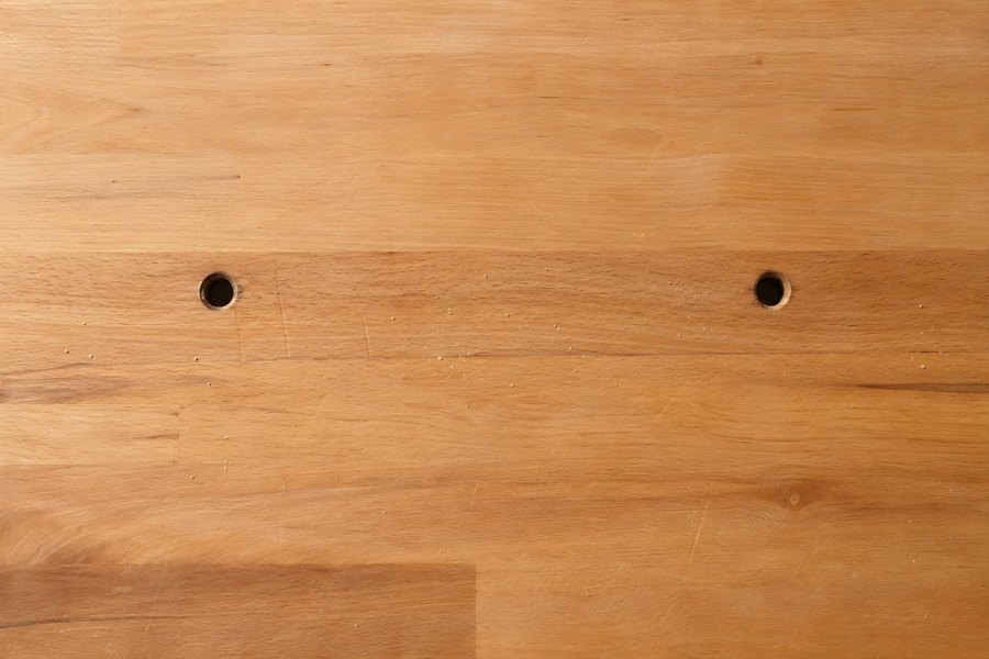 Wooden workbench surface with drilled bench dog holes and scattered sawdust, empty rustic wood texture background with copy space